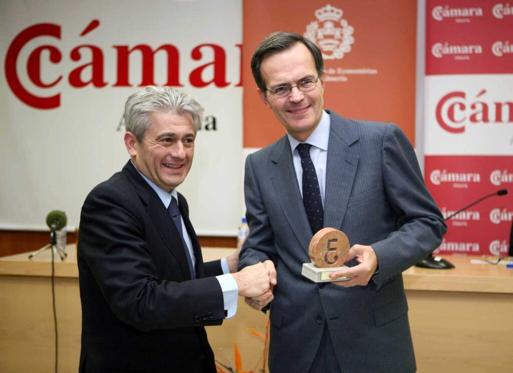 Foto de dos hombres dando un apretón de manos y uno con un premio