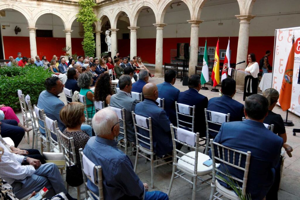Foto de una mujer dando un discurso con gente atendiendo