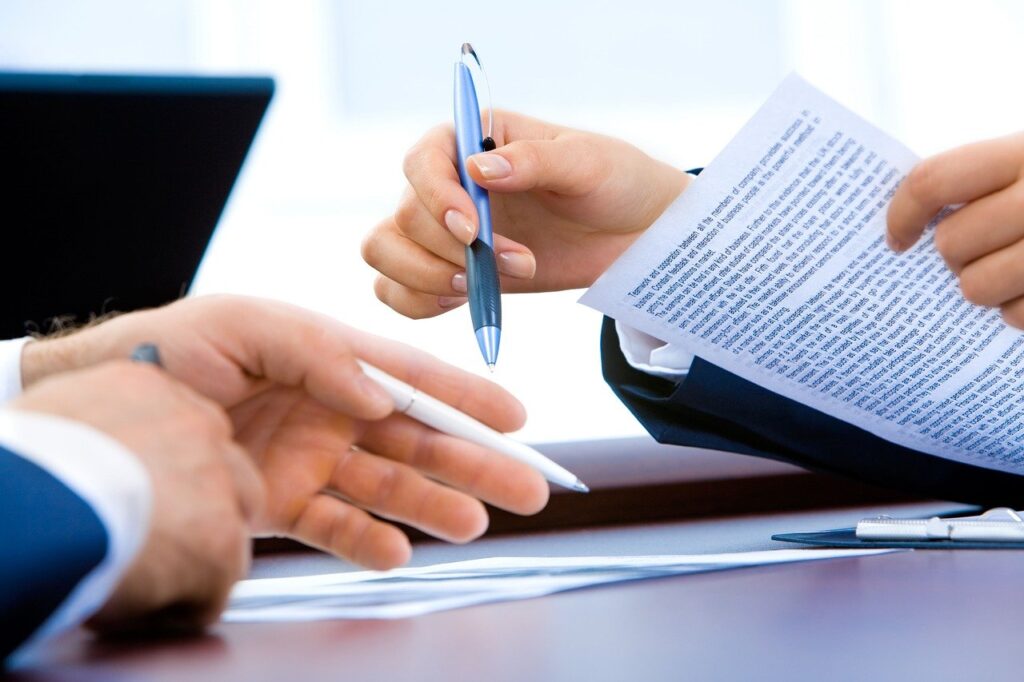 Foto de dos personas escribiendo en un papel