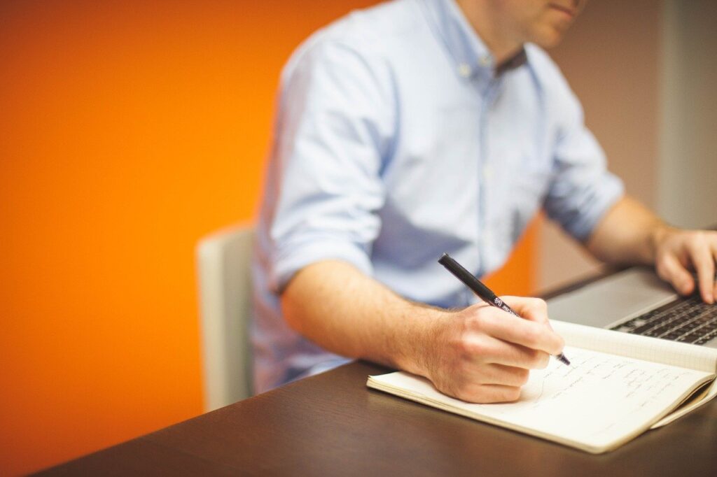 Foto de un hombre escribiendo en una libreta