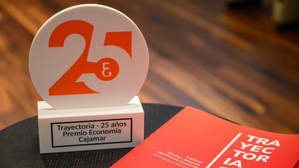 Trofeo conmemorativo del 25 aniversario del Colegio de Economistas junto a material de la publicación Trayectoria 25.